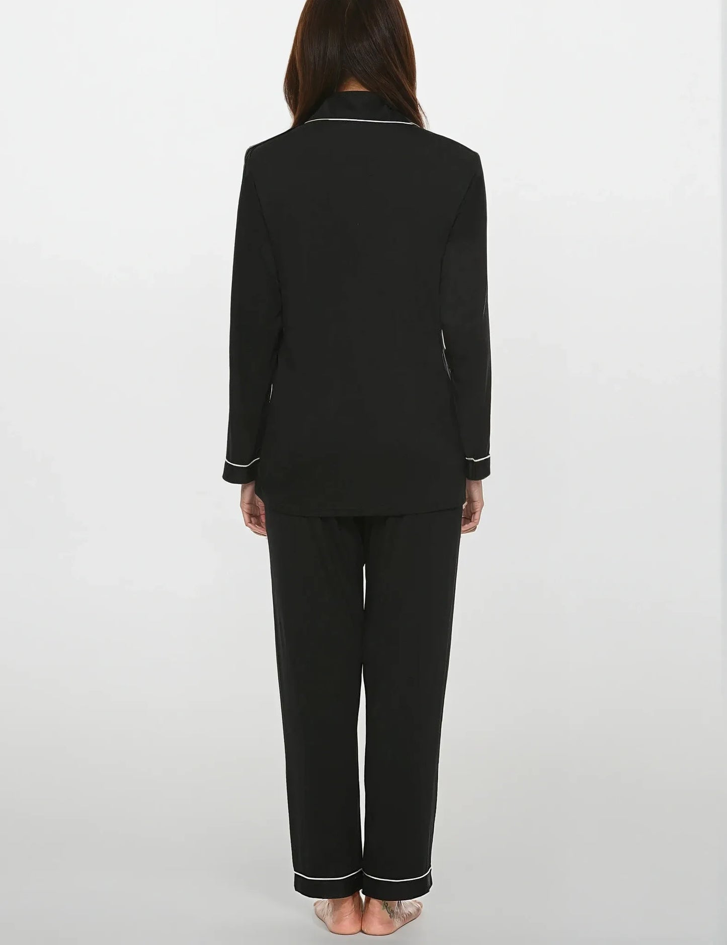 Back view of women's black bamboo pajama set with white piping – full sleeves and relaxed fit by Prana Poshak