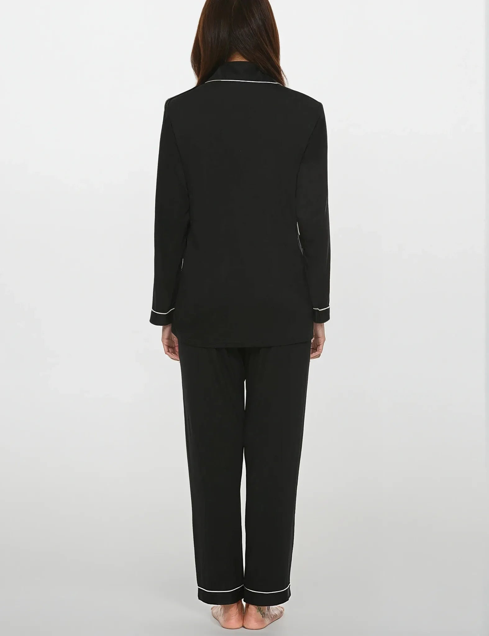 Back view of women's black bamboo pajama set with white piping – full sleeves and relaxed fit by Prana Poshak