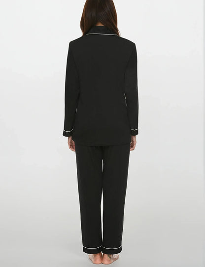 Back view of women's black bamboo pajama set with white piping – full sleeves and relaxed fit by Prana Poshak